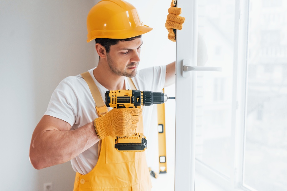 Handyman in yellow uniform installs new window by using automatic</div>
<a class=